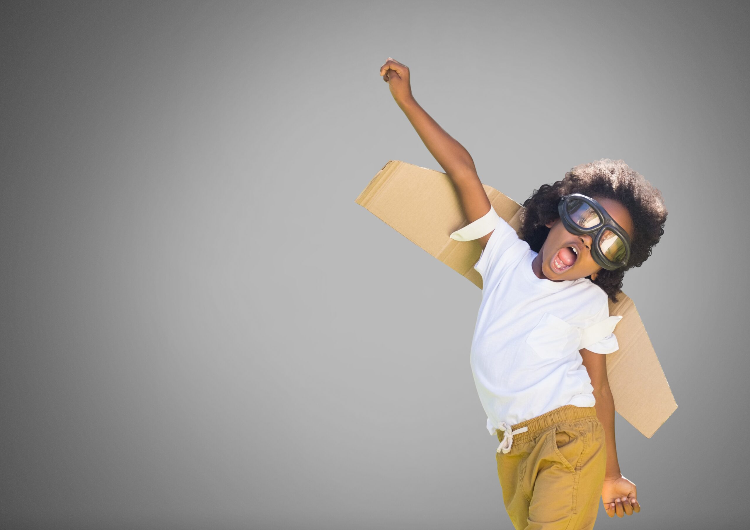 Digital composite of Kid against grey background with cardboard wings